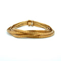 A multi-strand wrap bracelet made of textured, segmented gold-toned metal, coiled on a plain white background.