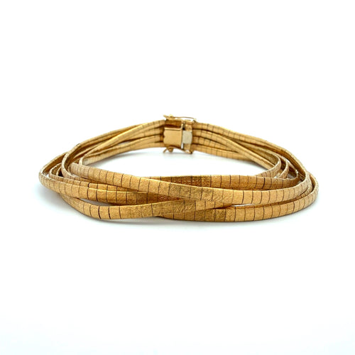 A multi-strand wrap bracelet made of textured, segmented gold-toned metal, coiled on a plain white background.