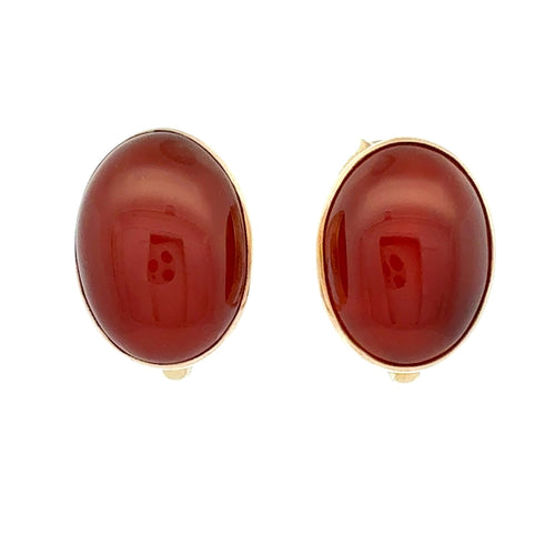 A pair of oval stud earrings featuring smooth, polished dark red cabochon stones set in a yellow gold-tone bezel, shown against a plain white background.