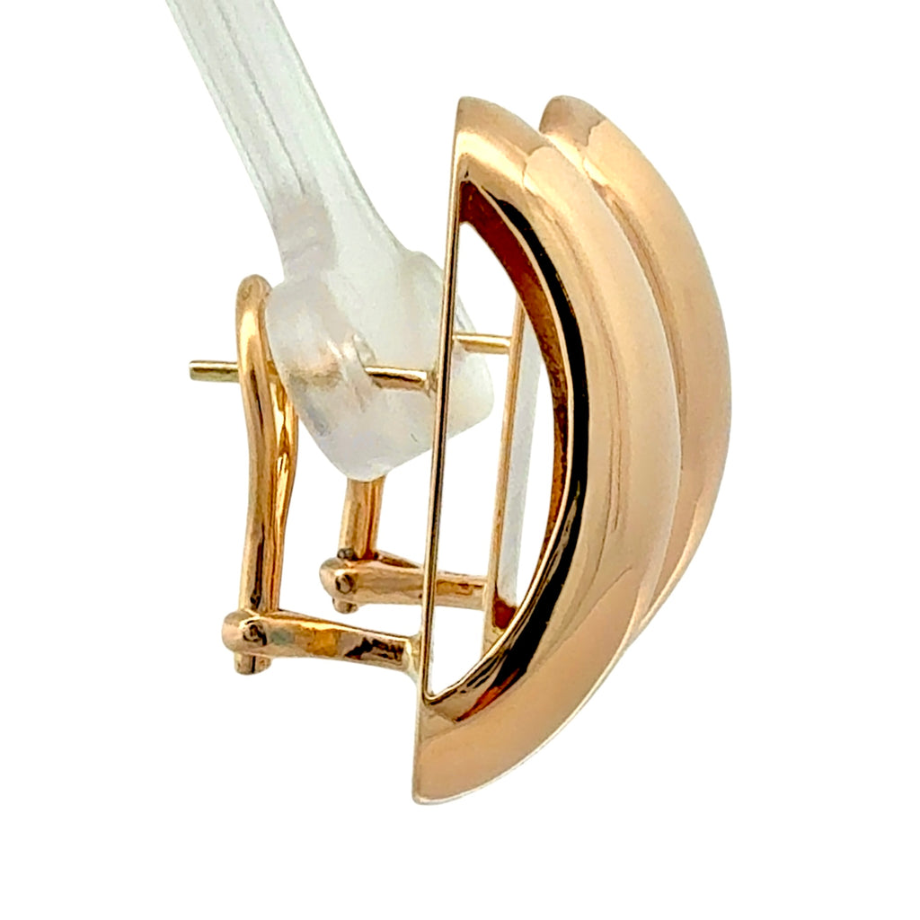 A close-up of a gold eyelash curler tool with a clear plastic push-on lash extension attached, set against a solid white background.
