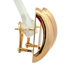 A close-up of a gold eyelash curler tool with a clear plastic push-on lash extension attached, set against a solid white background.