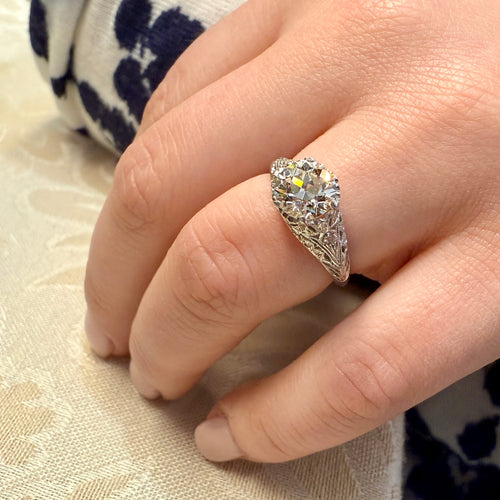 Close-up of a hand wearing a diamond ring on a textured fabric background