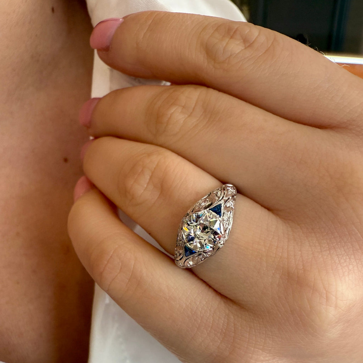 Close-up of a hand wearing a decorative ring with a white background