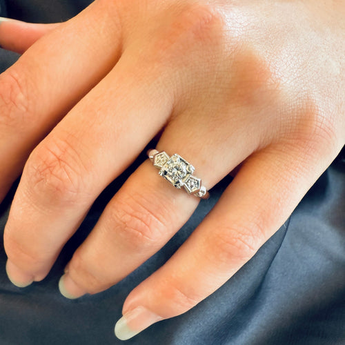 Close-up of a hand wearing a diamond ring on a dark fabric background