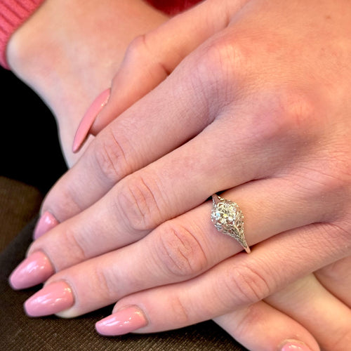 Close-up of a hand wearing a decorative ring with pink nail polish on a blurred background