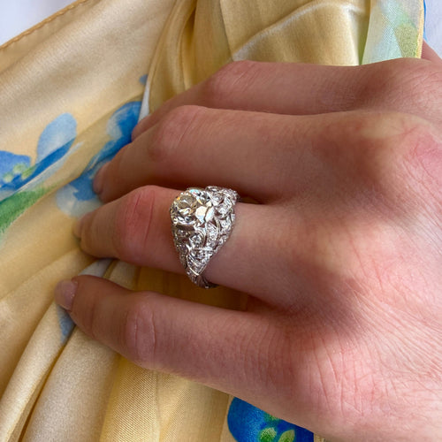 Hand wearing a diamond ring on a floral fabric background