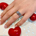 Hand wearing a diamond ring with red heart-shaped objects on a textured surface