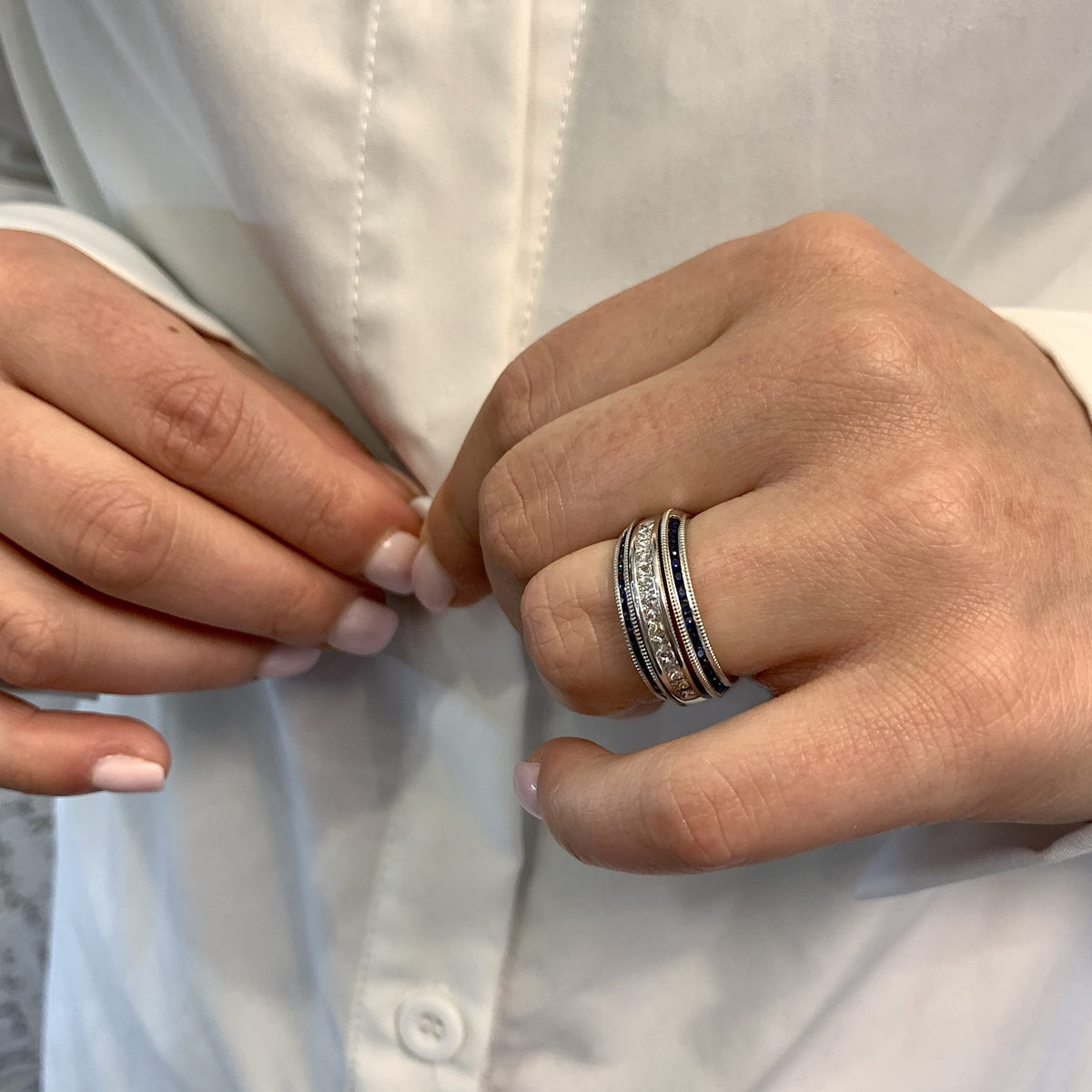 Close-up of hands with a ring buttoning a white shirt