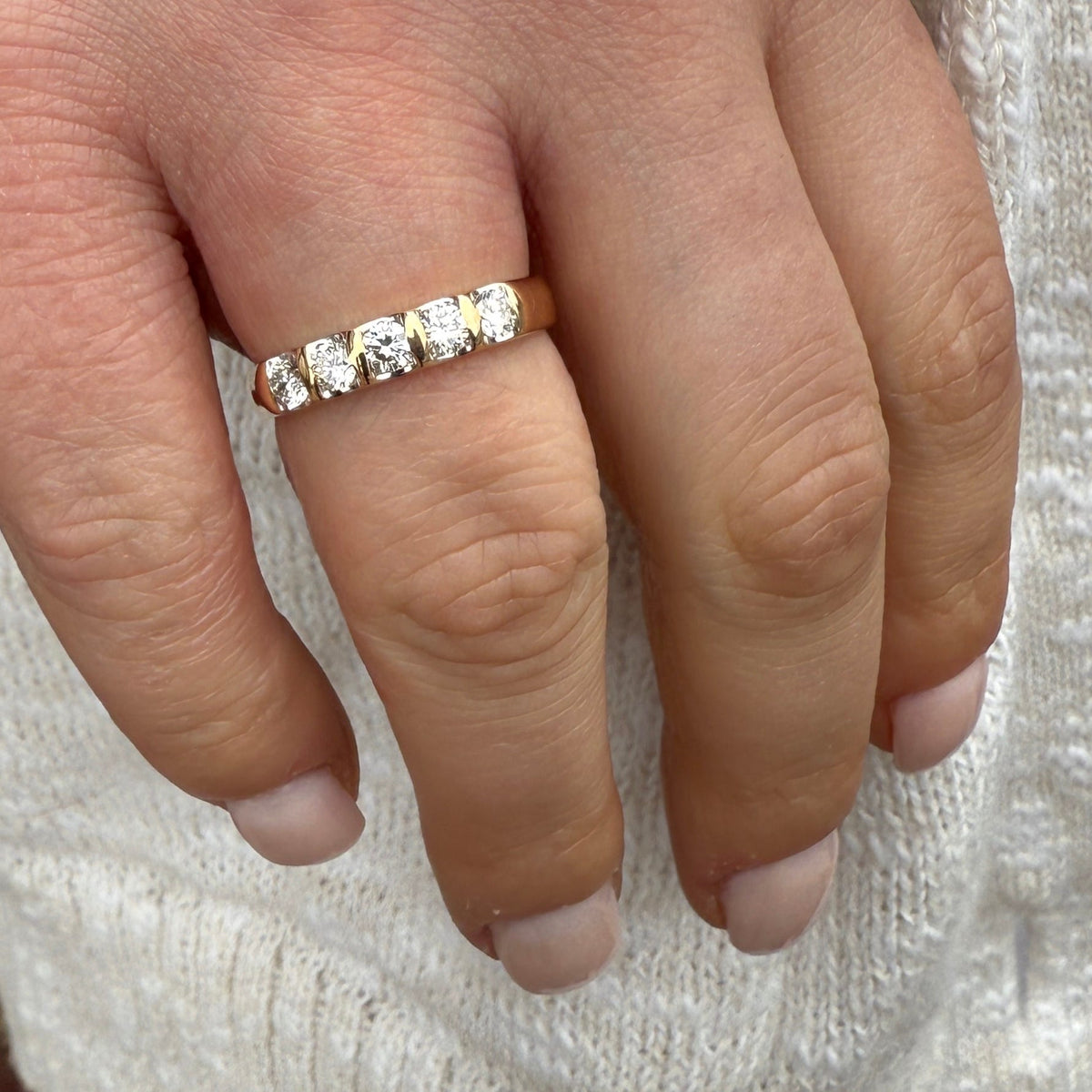 Close-up of a hand wearing a diamond ring on a textured white background
