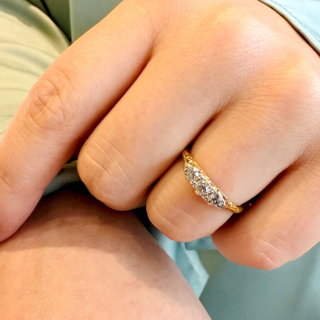 Close-up of a hand wearing a gold ring with diamonds.