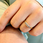 Close-up of a hand wearing a gold ring with diamonds.