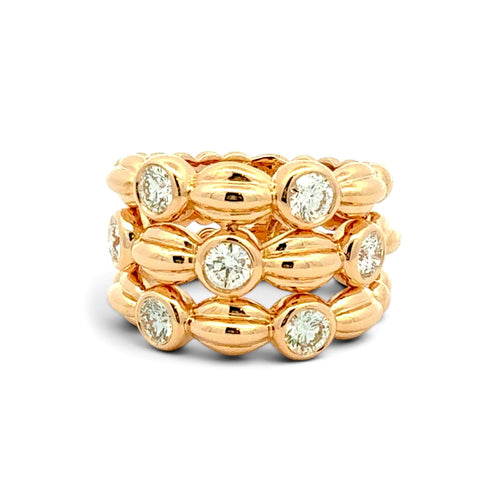 A gold multi-band ring featuring textured barrel-shaped beads and round clear gemstones, photographed on a clean white background.